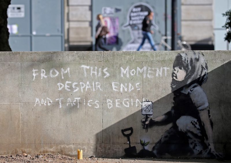On a wall, the words "From this moment despair ends and tactics begin" are painted.
