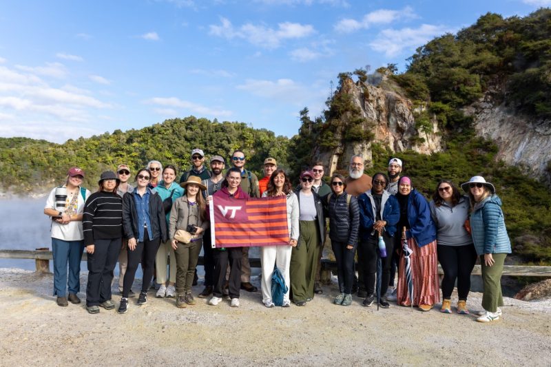 a group photo in front of volcanic lake with a virginia tech flag