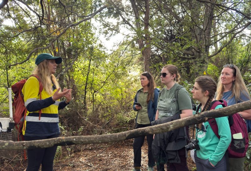 woman in yellow coat (at left) shows wildlife practices in the field
