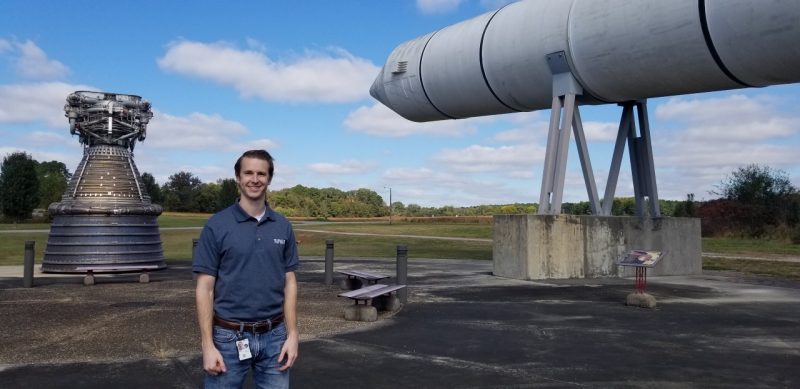 Daniel Patton stands by a rocket engine and solid rocket booster displayed at NASA’s Marshall Space Flight Center.