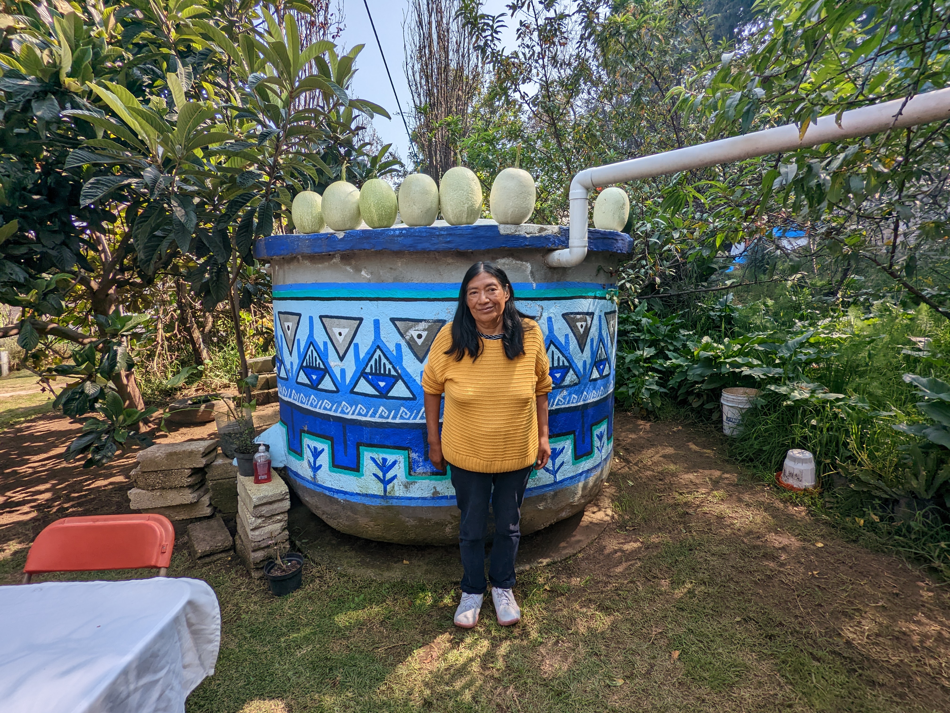 Elena, owner of an Isla Urbana rainwater catchment system, poses next to her rainwater tank, which holds enough water to fulfill her family's needs for 8 months out of the year; Photo: Tracey Coe